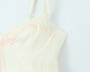 Dettaglio dell'abito in lino beige con pizzo bianco e fiocco in nastro rosa