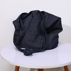 Detail of deep blue denim tote bag featuring wide strap knot and large capacity design