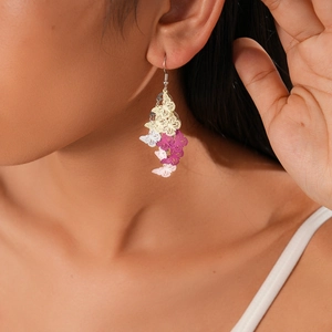 Detail of gradient butterfly drop earrings worn by model with light metallic finish