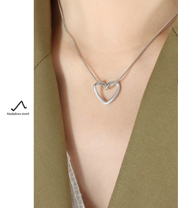 Macro detail of a silver stainless steel heart pendant necklace worn on a model