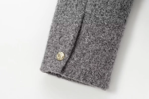 Close-up of grey tweed texture sleeve featuring a decorative gold button detail