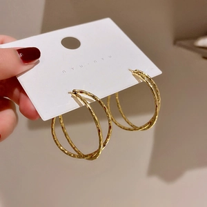 Detailed view of gold hoop earrings with hammered texture on a white display card