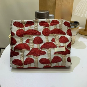 Close-up of rectangular makeup bag featuring red mushroom jacquard on beige fabric