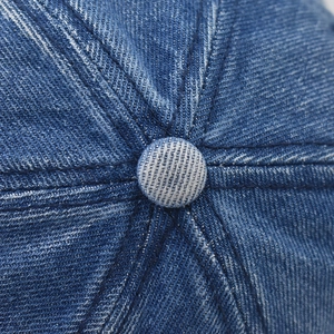 Macro shot of dark blue denim baseball cap top with button and stitching details