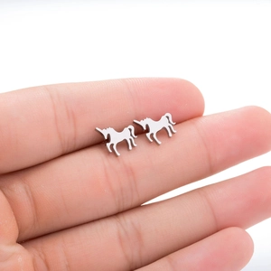 Macro detail of silver unicorn stud earrings held for size comparison on fingertips