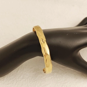 Close-up of golden hammered texture cuff bracelet on model with elegant metal finish