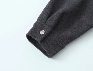 Close-up of charcoal gray wool jacket cuff with a single metallic round button