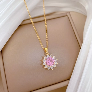 Detail of gold flower necklace with pink gemstone pendant on beige jewelry box