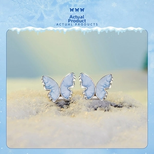 Macro view of blue enamel butterfly stud earrings on snow textured background
