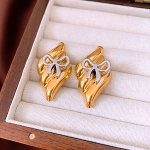 Macro shot of elegant silver bow earrings on a gold base with vintage textured leaf pattern