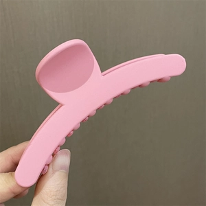 Primer plano de una pinza para el pelo con flor rosa mate sostenida en la mano