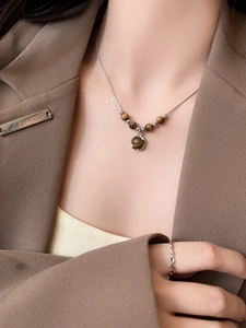 Detail of tiger eye stone pendant necklace and silver twist ring on professional attire