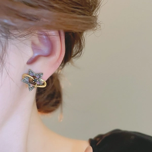 Close-up of golden Saturn earring with dark bead and crystals worn by a model