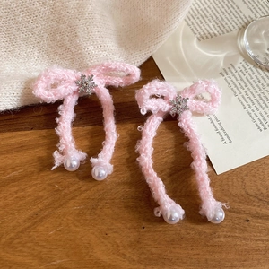 Detail of pink knitted bow hair clips with snowflake rhinestones and pearl drops on wood