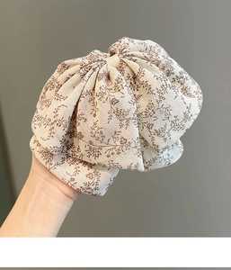 Détail d'une pince à cheveux élégante avec nœud en mousseline beige à motif fleuri