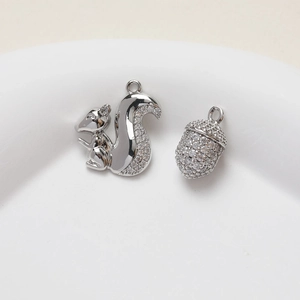 Detailed close-up of squirrel and pinecone charms with sparkling zircon inlay for jewelry