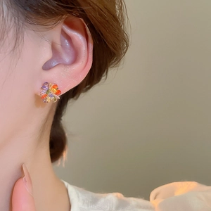 Macro shot of colorful crystal flower stud earrings worn on ear showing intricate details
