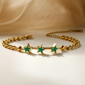 French style gold-plated star charm bracelet with green shell inlay on a soft background