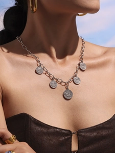 Silver multi-coin pendant necklace with embossed details shown on model with blue sky background