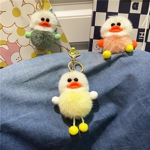 Detailed view of yellow green and pink fluffy plush duck keychains with golden metal hooks
