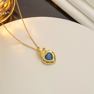 Close-up of golden heart necklace with deep blue gemstone and small diamonds inlay