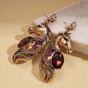 Detail view of vintage horse head earrings with red oval gemstones and purple rhinestones