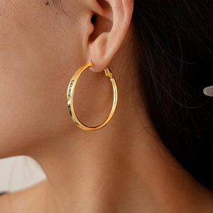 Detailed close-up of golden hoop earrings featuring the CELINN engraved letter design