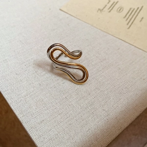Detail of 18k gold plated stainless steel S-shaped wave ring with gold and silver dual tones
