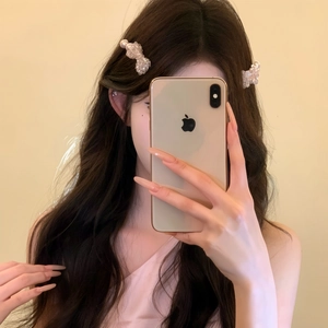 Detailed view of elegant pearl bow hair clips worn on long wavy brown hair for styling