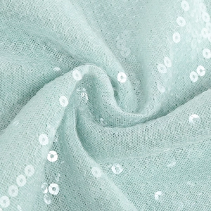 Detalle de tela de malla verde menta con lentejuelas brillantes y drapeado suave