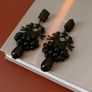 Gothic angel heart earrings with black crystals and beaded tassels on a vintage book