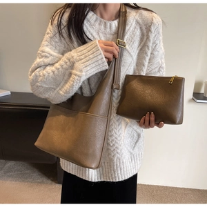 Detailansicht der großen braunen Kunstledertasche und passende Clutch an einem Modell