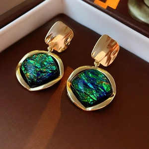 Macro detail of vintage gold diamond-shaped earrings with green resin gemstones