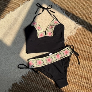 Detail of handmade crochet floral trim on a black high-waisted bikini set with S-size label