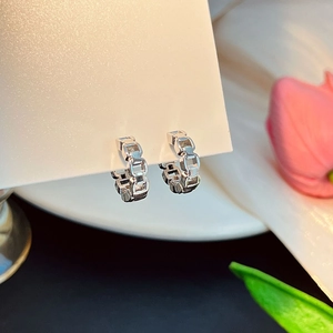 Vue macro de boucles d'oreilles géométriques en argent avec perles et cristaux