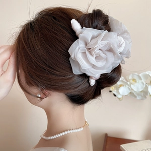 Vue détaillée d'une pince à cheveux rose en tissu blanc cassé avec perles sur satin