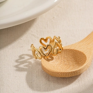 Retro gold hollow heart shaped ring displayed on a wooden spoon with aesthetic shadows