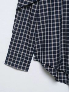 Macro detail of curved hem and sewing stitches on a plaid long-sleeve shirt