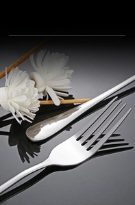 Close-up of mirror-polished stainless steel forks and spoons on reflective black background