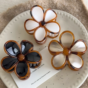 Detailed view of three vintage amber flower hair claws on a ceramic display plate