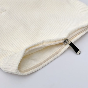 Detail of cream corduroy makeup bag featuring a smooth silver metal zipper closure