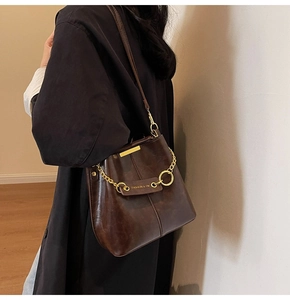 Close-up of retro dark brown leather bucket bag featuring elegant gold chain strap