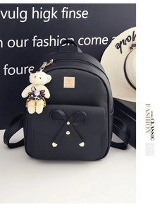 Detail of black PU leather backpack with bow decoration and a cute bear charm accessory