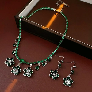 Detail showing green zircon flower and water drop pendant necklace set on dark background