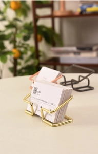 Detail of minimalist gold wire business card holder in a professional office setting