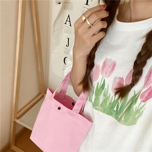 Minimalist pink canvas lunch bag held by a model against a soft cream background