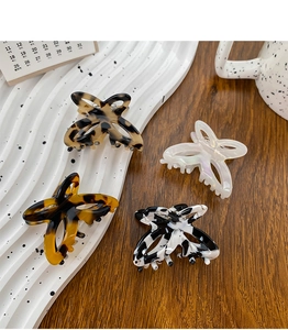 Detailed close-up of four butterfly acetate hair claws in tortoise shell and marble patterns