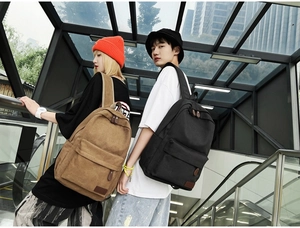 Modern canvas backpacks in khaki and black worn by models on an escalator in the city