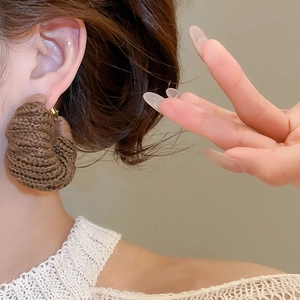 Primo piano di orecchini a cerchio in maglia marrone scuro con trama a spirale a mano