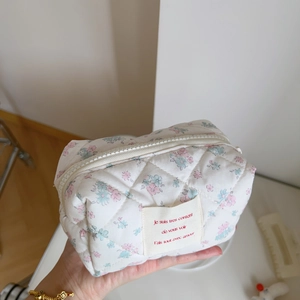 Detailed macro of pink floral quilted makeup bag with French text label decoration